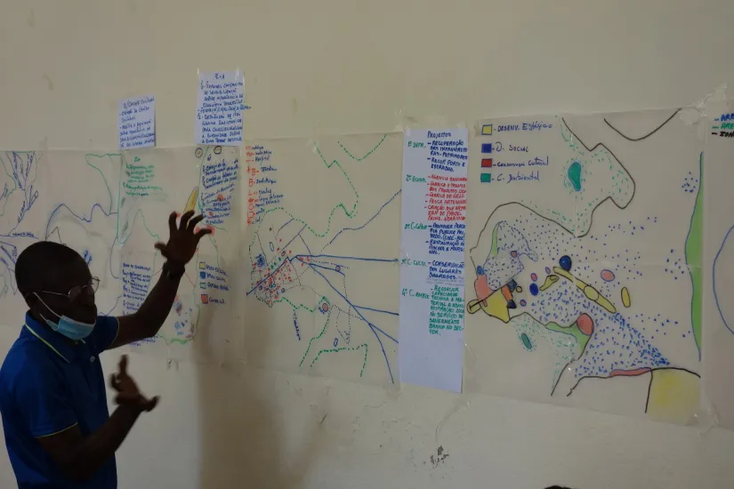 Workshop participant stands in front of a map during a workshop  in Bolama, Guinea Bissau